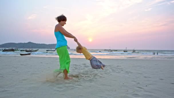 Madre oscillante bambino figlio da mani sulla spiaggia — Video Stock