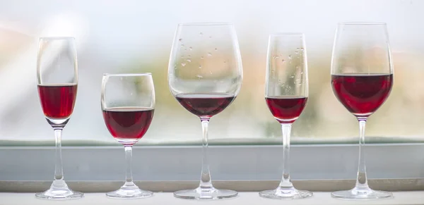 五杯不同的红酒在窗前 免版税图库图片