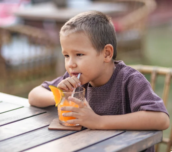 可愛い男の子が屋外カフェでジュースを飲む — ストック写真