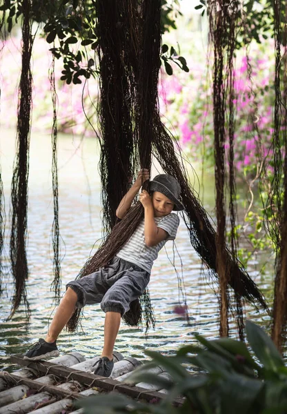 ガジュマルの木で湖を楽しんでいる男の子 — ストック写真
