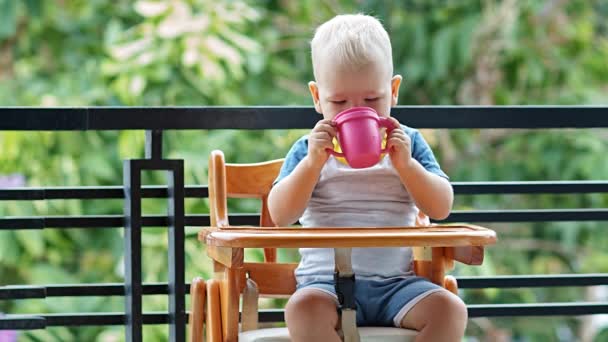 Toddler chłopiec spragniony chętnie pije kubek jogurtu — Wideo stockowe