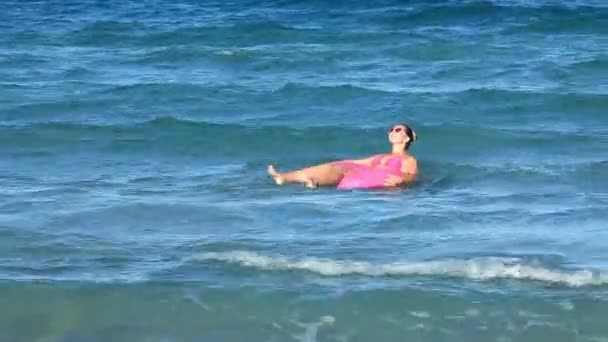 Mädchen schwimmt auf der Röhre durch die Wellen — Stockvideo