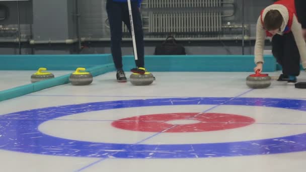 Flicka papiljotter rullar en curling stone — Stockvideo