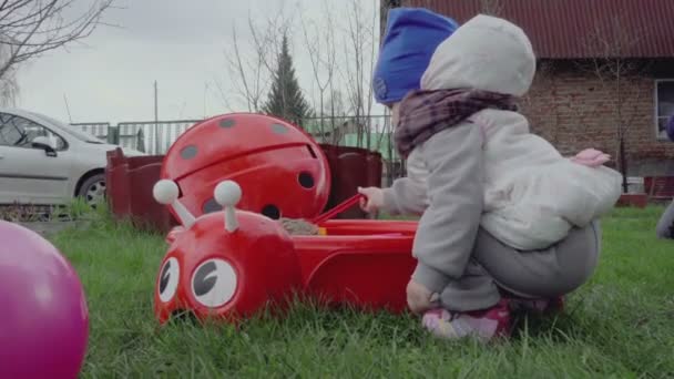 Girl playing in the sandbox on the lawn — Stock Video