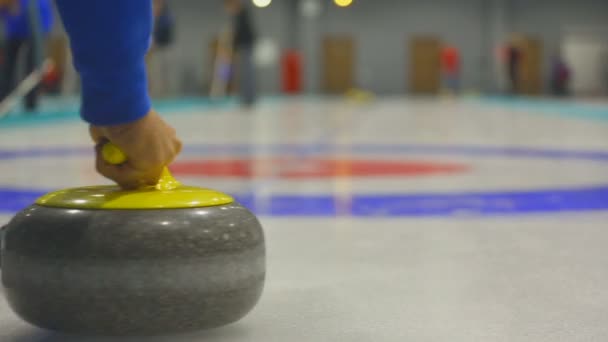 Spelaren rullar en curling stone — Stockvideo