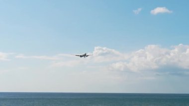 Okyanus kıyısındaki piste yaklaşan bir uçak var.