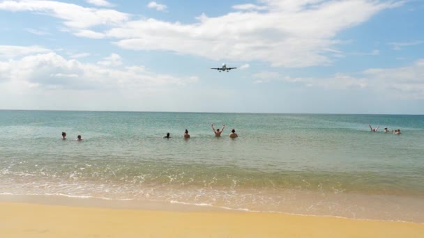 在Mai Khao海滩的人们在海里游泳，看着飞机降落在Phuket机场. — 图库视频影像