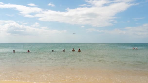 在Mai Khao海滩的人们在海里游泳，看着飞机接近Phuket机场. — 图库视频影像