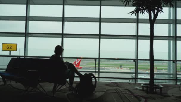 Kobieta przy oknie terminalu na lotnisku — Wideo stockowe