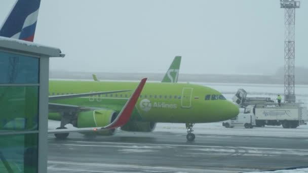 Vliegtuig taxiën naar de terminal in besneeuwde weer — Stockvideo