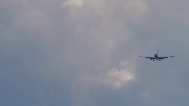 Gri gökyüzüne iniş yapan bir uçak yaklaşıyor.