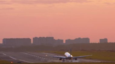 Gün batımında inen bir uçağın arka görüntüsü