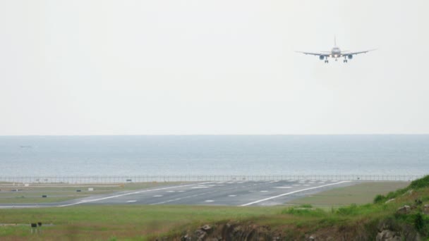Авиалайнер летит для посадки на фоне моря — стоковое видео