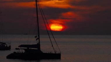 Günbatımının arka planında bir yatın silueti