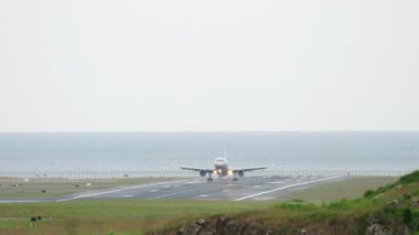 Airplane landing on the runway, sea background