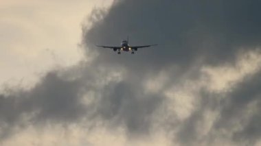 Bulutlu gökyüzünün arka planına inen uçak