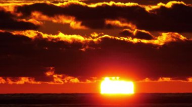 Parlak gün batımı ve deniz kenarındaki bulutlar