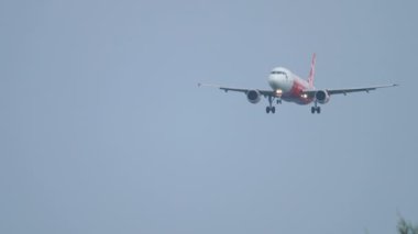 Jet bulutlu arka planda havaalanına geliyor.