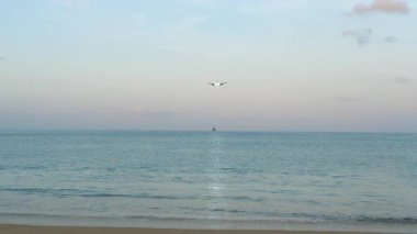 İniş için inişe geçen işaretsiz bir jet uçağı, açık mavi gökyüzüne karşı cephe görüşü. Denizin üzerinde uçan bir uçak. Seyahat ve modern hava taşımacılığı kavramı.