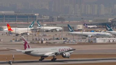 HONG KONG - 29 Ocak 2025: uçak Boeing 777, Katar Kargo A7-BFX Chek Kap Kok havaalanına indikten sonra fren yapıyor, yan görüş. Kargo jeti geliyor. Beneklenme