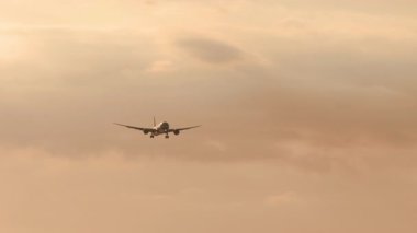 Gün batımında gökyüzüne inen bir uçağın sinematik görüntüleri. Uçak uçuyor.