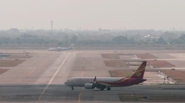 BANGKOK, THAILAND - 15 Mart 2025: Hainan Havayolları Boeing 737, B-1389 taksicilik, yan görüş. Yolcu uçağı pist ya da taksi yolunda. Seyahat kavramı