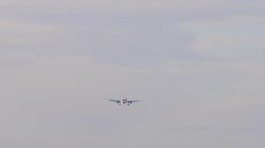 Ticari jet bulutlu gökyüzüne inmek için iniyor. Hava yolculuğu ve havacılık konuları için mükemmel..