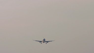 Tanımlanamayan bir üniforması olan jet uçağı inişe geçiyor, ön görüş, uzak çekim.