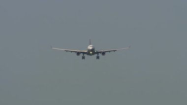 Şehrin üzerine inmek üzere olan görünür bir havayolu markası olmayan yolcu uçağının ön görüntüsü.