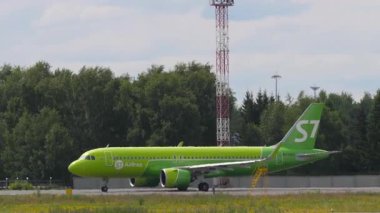 NOVOSIBIRSK, RUSSIAN FEDERATION - 15 Temmuz 2022: S7 Airlines Airbus A320, plakası RA-73457, Tolmachevo Havalimanı pisti boyunca taksicilik yapıyor. Kalkıştan önce hareket eden yeşil uçağın yan görüntüsü