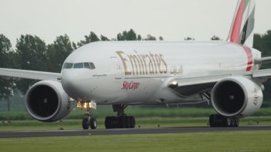 AMSTERDAM, NETHERLANDS - 25 Temmuz 2017: Geniş gövdeli Emirates kargo uçağı Boeing 777, pistte A6-EFO, orta atış. Havaalanında büyük bir nakliye uçağı.