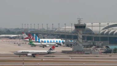 BANGKOK, THAILAND - 15 Mart 2025: Airbus A320 Jet Star Airlines ve Airplane Spring Airbus A320 Suvarnabhumi Havaalanında taksicilik. Terminalde sıra sıra bekleyen uçaklar. Başka bir uçak kalkıyor.