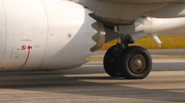 Uçak motoru ve iniş takımlarını apronda park halindeyken yakın çekime alın. Havacılık, yer operasyonları ve modern hava yolculuğu kavramları için mükemmel.