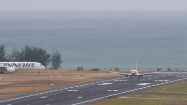 PHUKET, THAILAND - 25 Şubat 2025: Phuket Havaalanına indikten sonra Nok Air Boeing 737 HS-DBQ frenleme. Kalkıştan önce Finnair Airbus A350. Seyahat kavramı