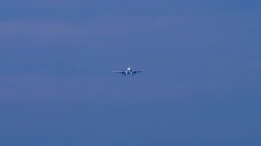 İniş için ışıkları açıkken bir jet uçağının görüntüsü. Gökyüzünde uçak, uzak çekim, ön manzara.