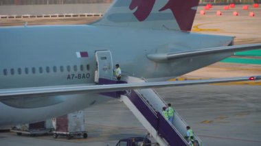 PHUKET, THAILAND - 4 Aralık 2018: Katar Havayolları Boeing 777, A7-BAO, havaalanı standına park edildi. Uçağa hareketli bir merdiven bağlandı ve yer ekibi merdivenlerden çıkıyor.