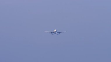 Mavi gökyüzüne inmek için inen bir jet uçağının silueti. Piste yaklaşan bir uçağın uzaktan görüntüsü. Havacılık, seyahat ve hava taşımacılığı kavramı