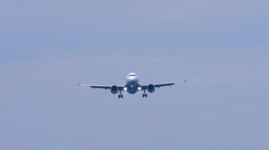 Tanımlanamayan bir üniforması olan jet uçağı inişe geçiyor, ön görüş, uzak çekim.