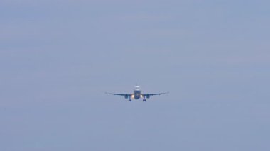 Tanımlanamayan bir üniforması olan jet uçağı inişe geçiyor, ön görüş, uzak çekim.