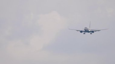 Tanımlanamayan bir üniforması olan bir jet yolcu uçağı iniş yapmak üzere. Gri gökyüzünde uçan uçak. Seyahat konsepti, güvenli uçuşlar, havacılık