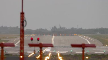 İniş ışıklarıyla aydınlatılmış boş bir havaalanı pistinin son görüntüsü. Hava sahnesi seyahat, ulaşım ve havaalanı teması için mükemmel.
