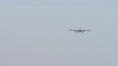 Tanımlanamayan bir üniforması olan dört motorlu dev bir uçak iniş yapmak üzere. Mavi gökyüzü arka planında bir uçak. Seyahat kavramı