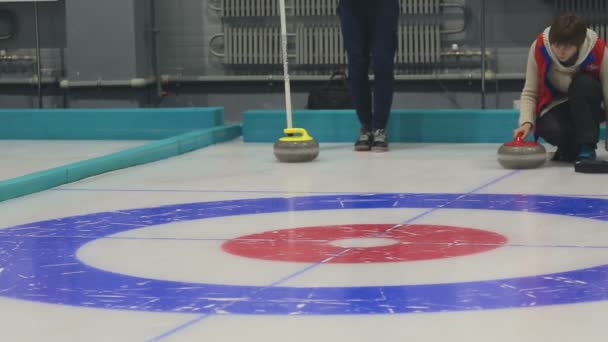Flicka papiljotter rullar en curling stone — Stockvideo