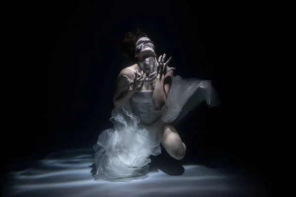 Girl Bride in Dead Man Skeleton Makeup Scares under Water. Halloween Concept