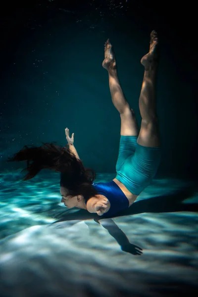 Dziewczyna zajmuje się jogą pod wodą w strojach sportowych. Asany i medytacja — Zdjęcie stockowe
