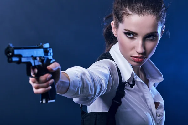 Beautiful sexy girl holding gun . smoke background — Stock Photo