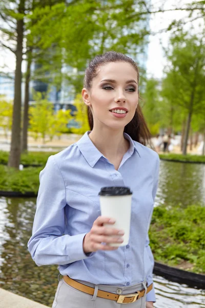 Businesswoman with coffee in park — Stock Photo, Image