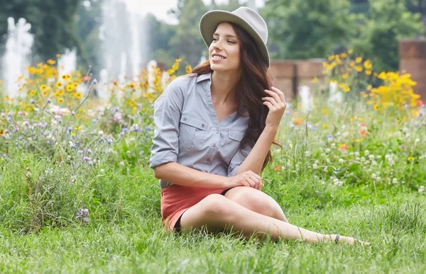 Våren kvinna sitter på gräs — Stockfoto