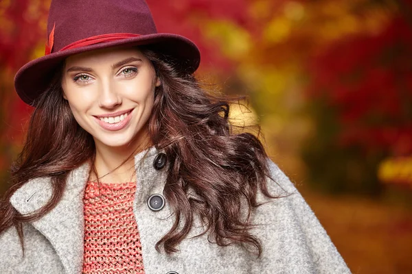 Vrouw bij achtergrond van rode en gele bladeren — Stockfoto