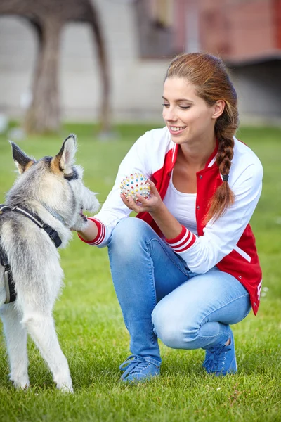 Красивая девушка, играющая с собакой на улице — стоковое фото
